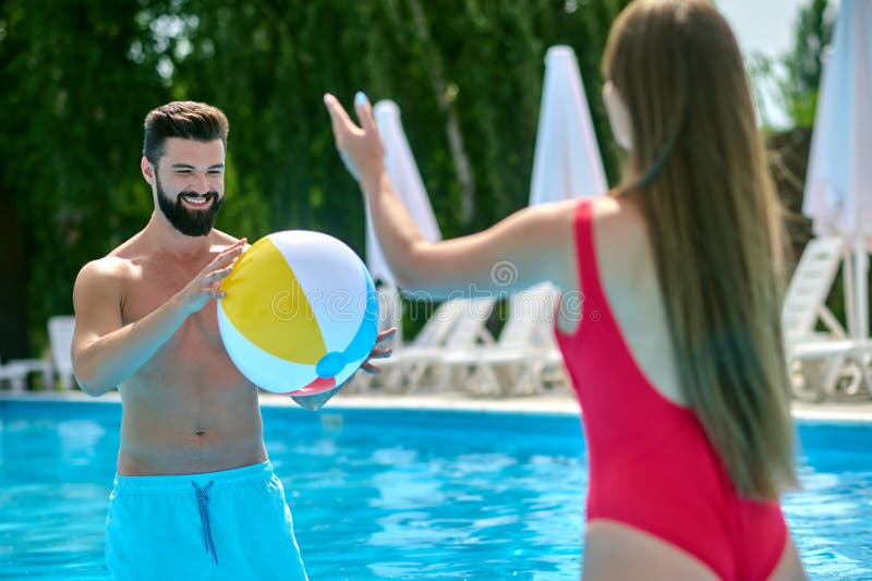Happy attractive couple having fun in pool with beach ball. stock photos
