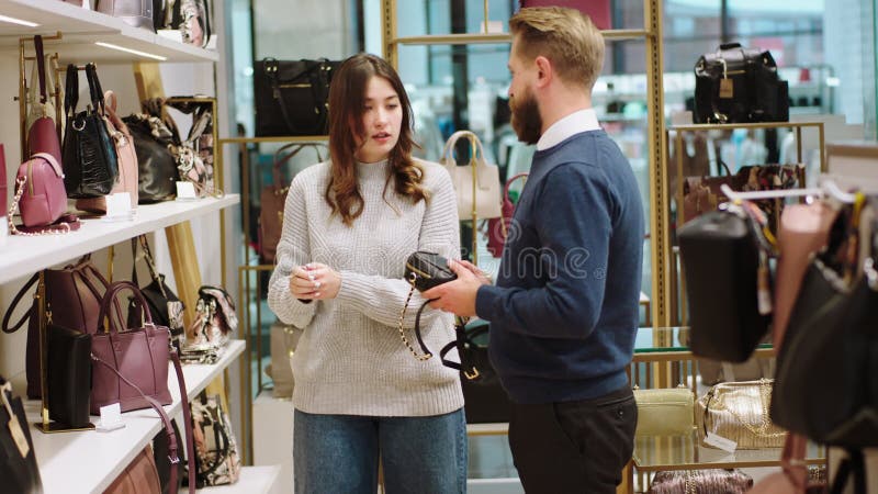 happy attractive salesman helping customer lady to choose one bag accessories store concept happy 240875678