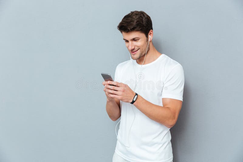 Happy attractive young man listening to music from smartphone