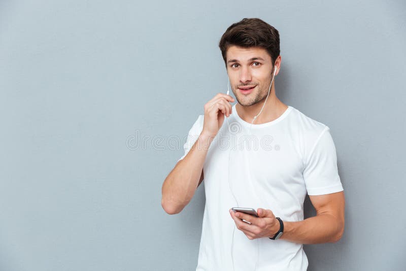 Happy attractive young man listening to music from smartphone