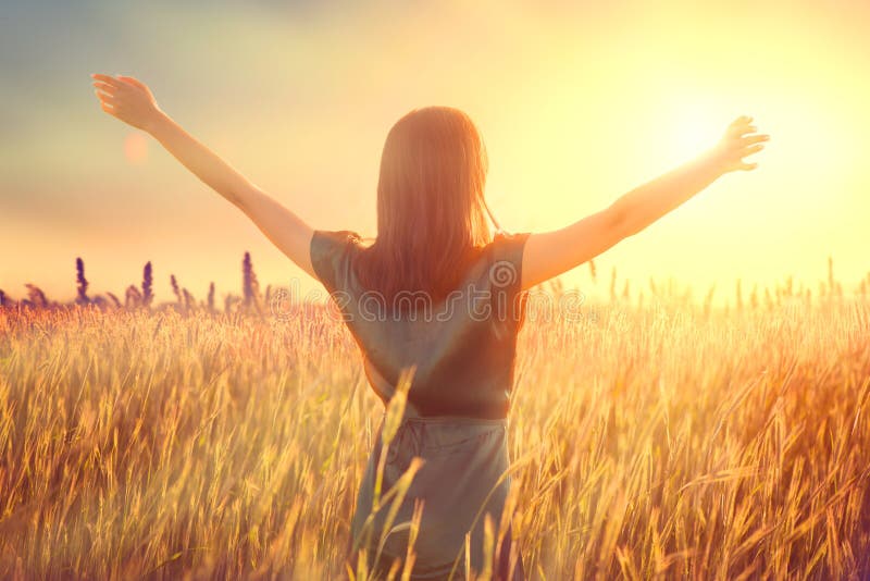 Happy autumn woman raising hands over sunset sky, enjoying life and nature. Beauty female on field looking on sun