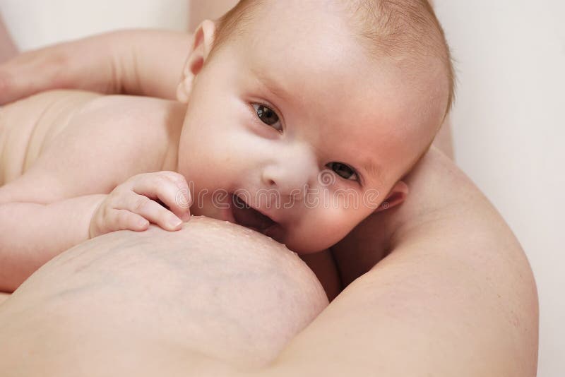 Bambino che ride mentre si mangia il latte dal seno della madre.