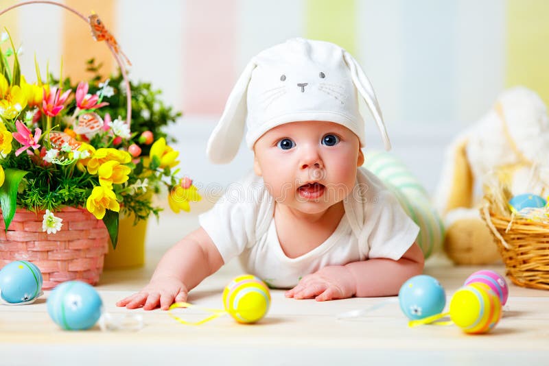 Happy baby child with Easter bunny ears and eggs and flowers