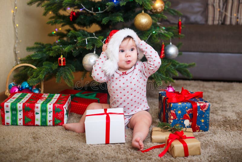 Happy Cute Baby Girl in Santa Claus Hat Holding Christmas Gifts at Christmas  Tree at Home Stock Photo - Image of cheerful, celebration: 131883364