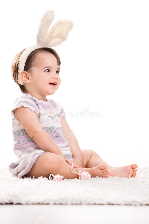 Happy baby girl in easter costume sitting on carpet, laughing. Isolated on white background. Lovely european female stock images, royalty-free photos and pictures
