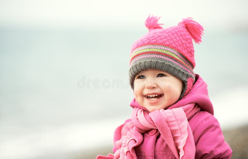 Happy baby girl in pink hat and scarf laughs