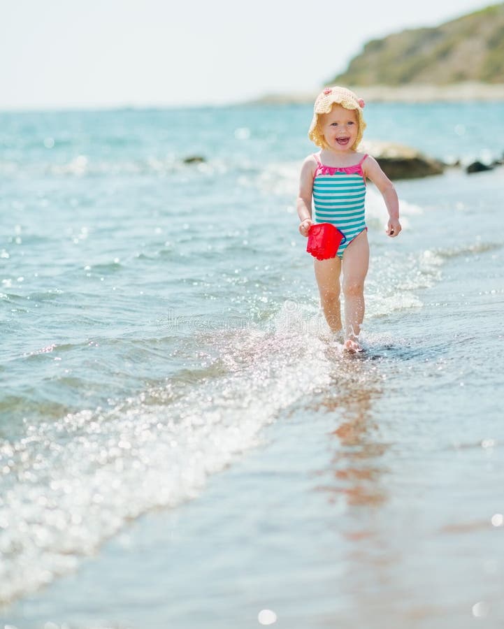 Happy Baby with Pail Running Along Seashore Stock Photo - Image of ...