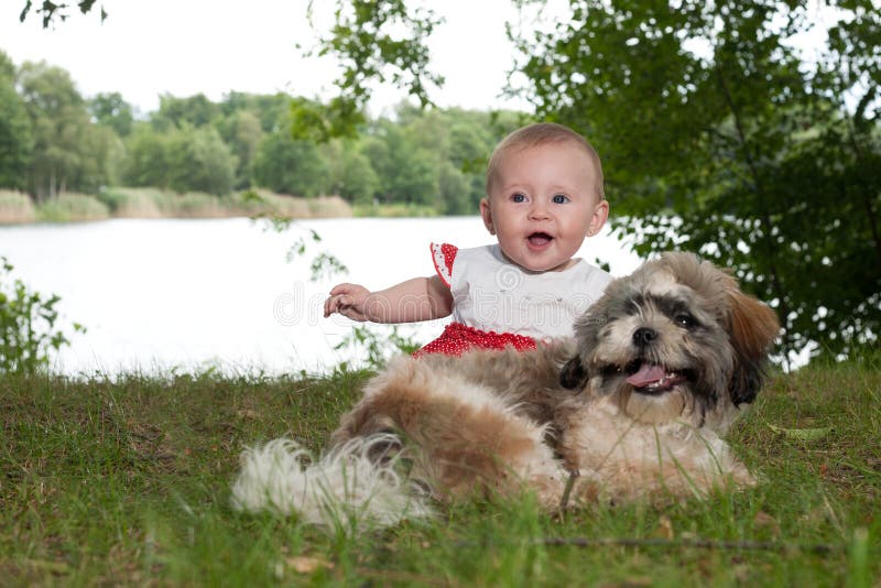 Happy baby and puppy near the lake