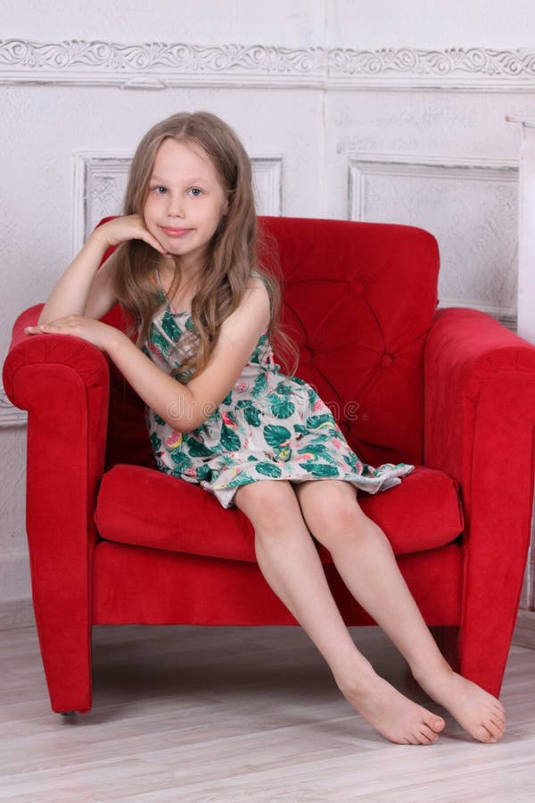 Happy barefoot little girl in dress sits
