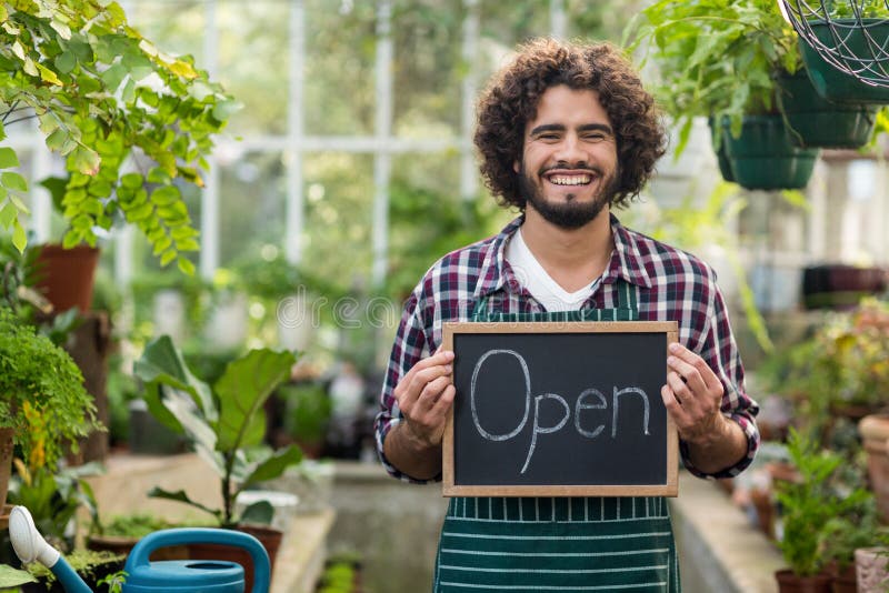 Happy bearded gardener holding open sign placard royalty free stock photo Happy bearded gardener holding open sign placard royalty free stock photo