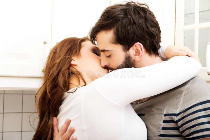Happy Beautiful Couple Kissing in the Kitchen. Stock Photo Image of