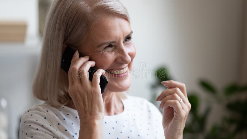 Happy beautiful mature woman making phone call close up