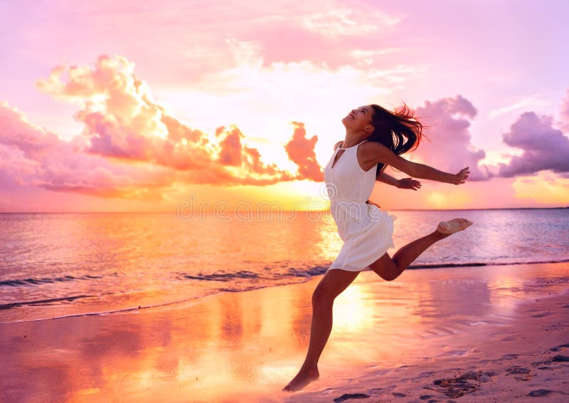 Happy beautiful woman running at beach sunset
