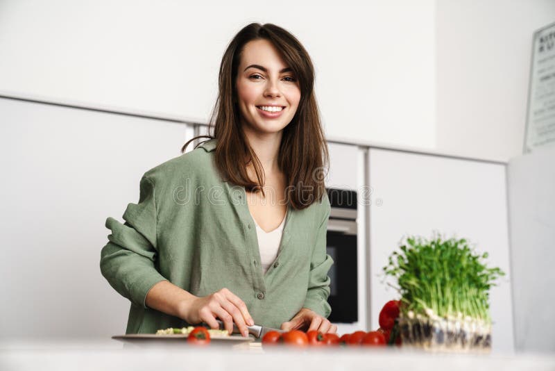 Happy beautiful woman smiling while making salad at home kitchen