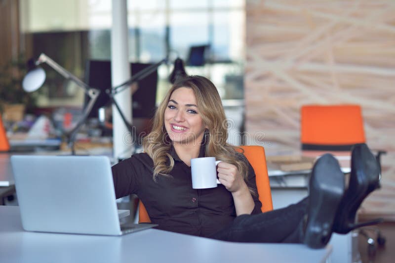 Happy beautiful young business woman sitting and talking on cell phone in office