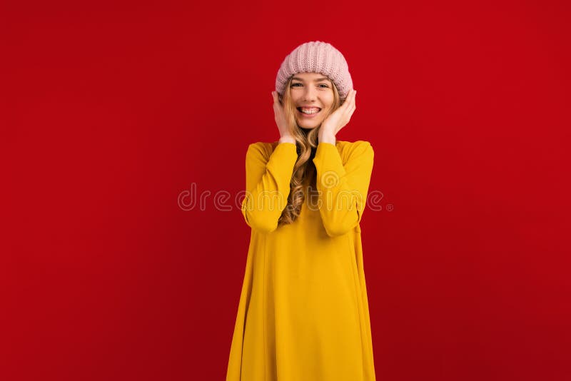 Happy beautiful young woman in a warm hat on her head, on a red background