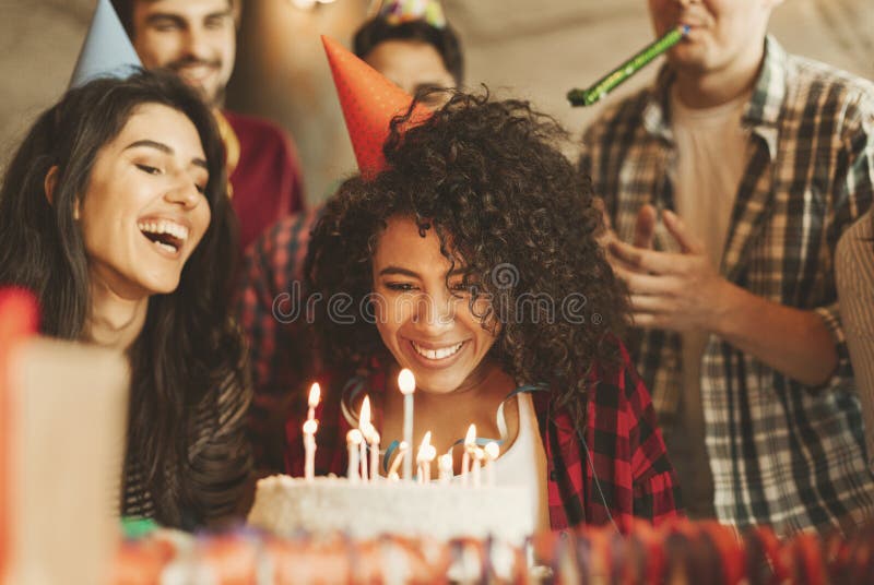 Excited girl ready to blow out candles on cake on birthday party with happy friends. Happy birthday dear friend concept