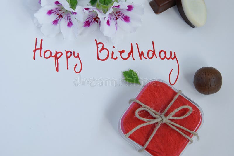 Happy birthday greeting card with gift box, fresh flowers and chocolates on white background