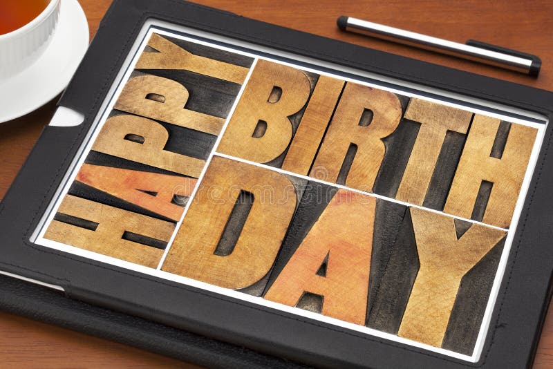 Happy birthday greeting card - word abstract in letterpress wood type on digital tablet with a cup of tea