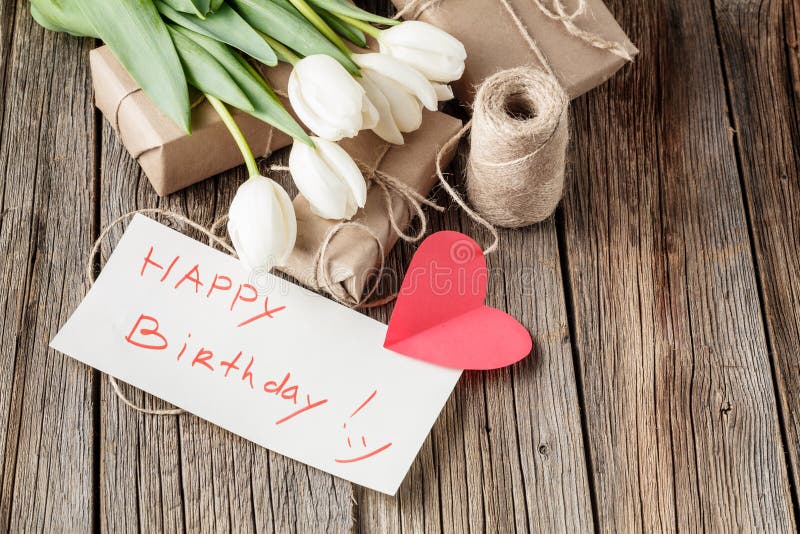 Happy birthday mesage with flowers on rustic table with flowers