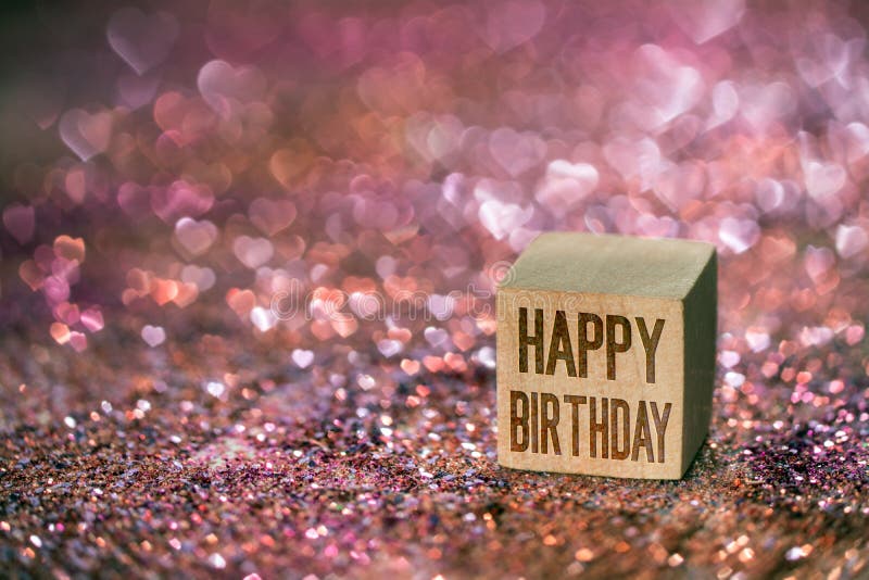 Happy birthday text written on wooden cube on color glitter with beautiful real heart shape bokeh light. Happy birthday text written on wooden cube on color glitter with beautiful real heart shape bokeh light