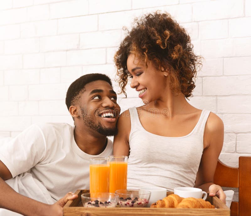 Happy black couple enjoying breakfast in bed