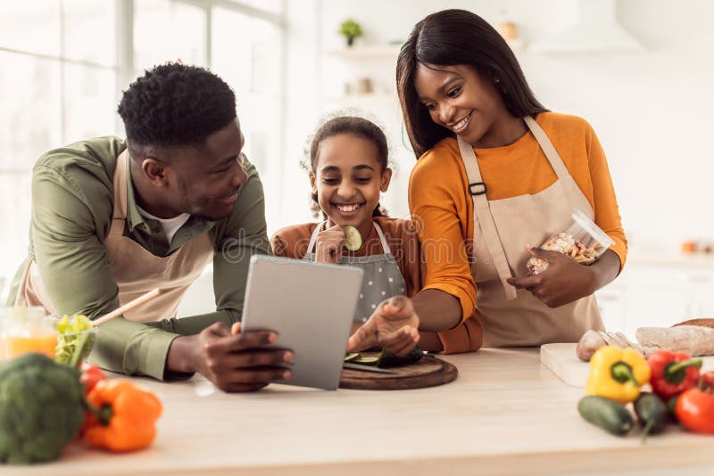 Black Family Cooking Using Digital Tablet Preparing Dinner in Kitchen