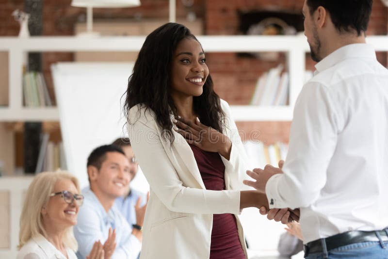 Happy proud black female employee get rewarded handshake caucasian boss