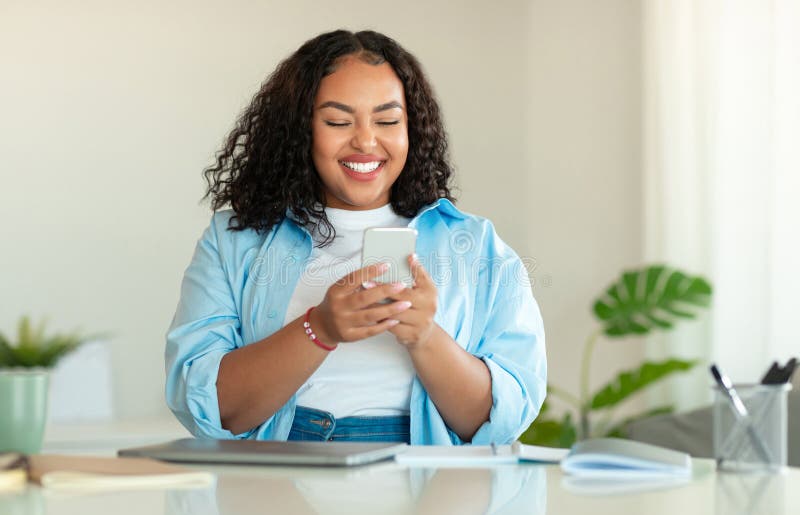 Happy Black Woman Using Mobile Phone Sitting In Modern Office stock photos