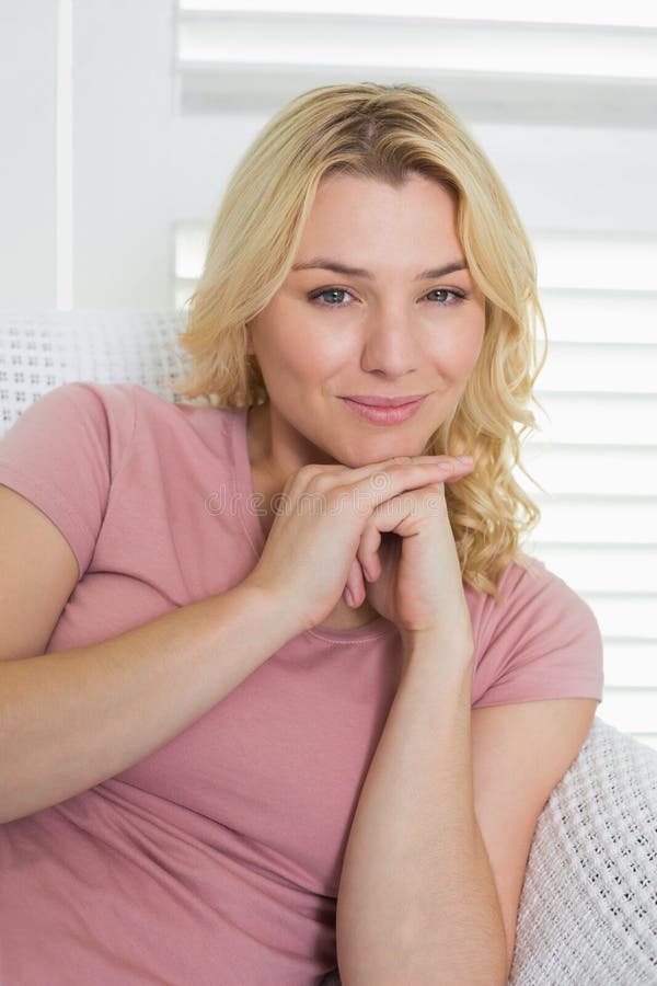 Happy Blonde Relaxing On The Couch Smiling At Camera Stock Image