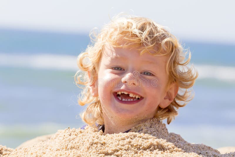 Rozkošný mladých šťastný chlapec na pláž hrať v piesku.