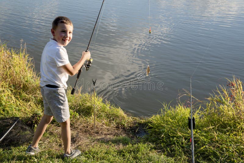 Šťastný chlapec chytil rybu. Chlapec rybaření na jezeře. Dítě drží rybářský prut. Malý rybář