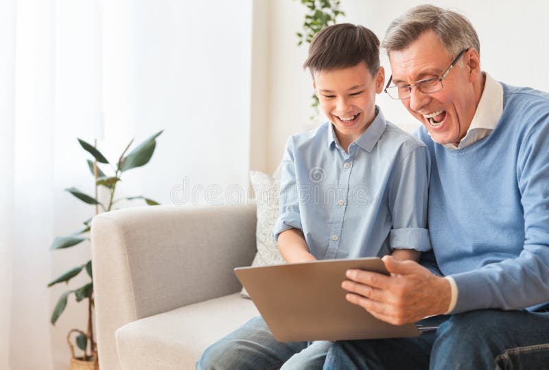 Happy Boy en zijn grootvader die laptop gebruiken die op Sofa zit