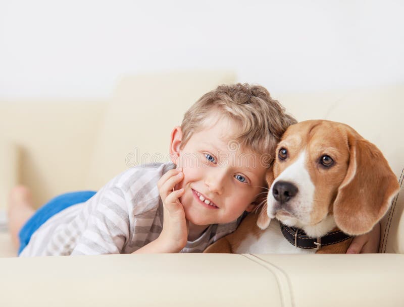 Happy boy with his dog lying on sofa