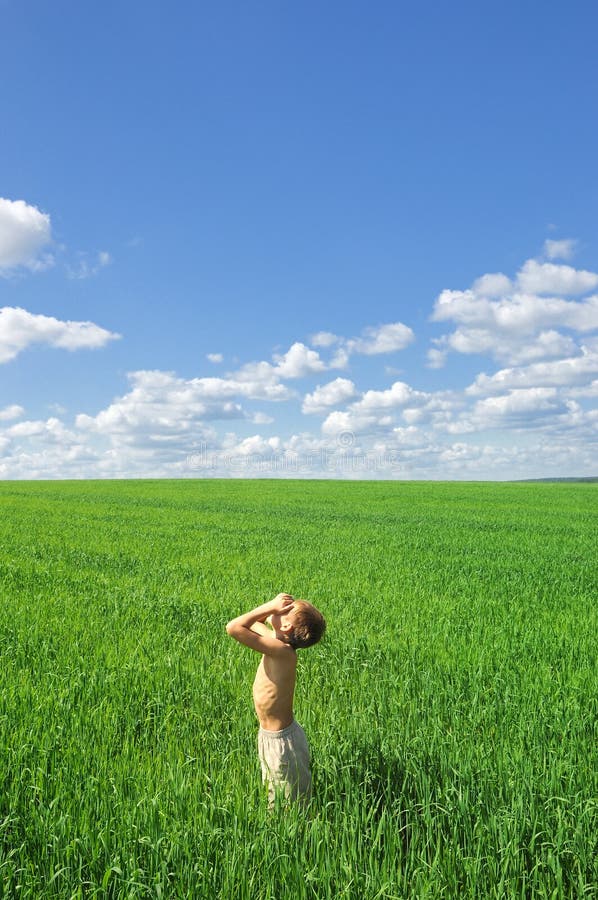 Happy boy looking to the sun on green field