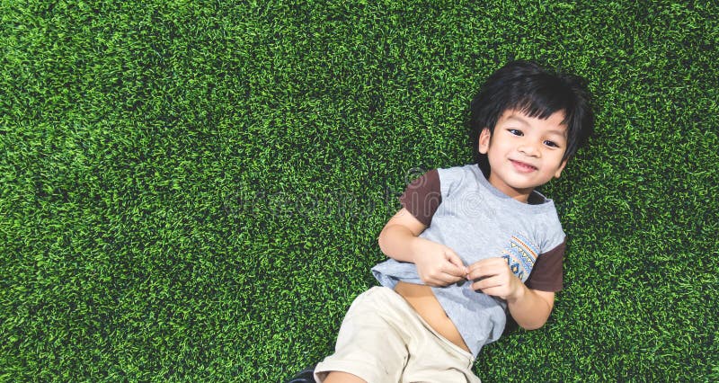 Happy boy is lying on artifact grass field