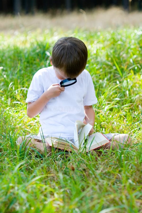 Happy boy with a magnifying glass and a book