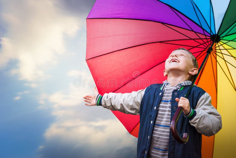 Happy boy portrait with bright rainbow umbrella