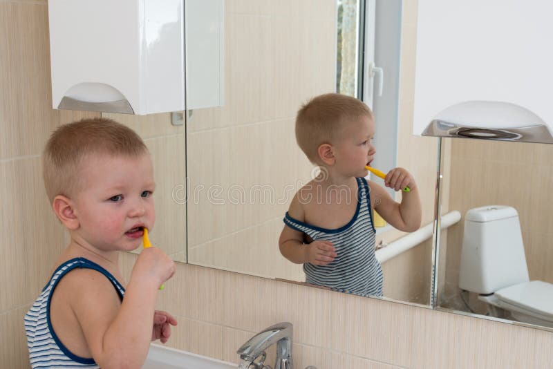 Happy boy taking bath in kitchen sink. Child playing with foam and soap bubbles in sunny bathroom with window. Little baby bathing