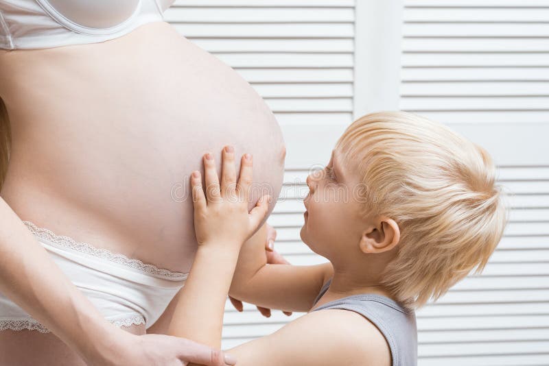 Happy boy touching belly of pregnant mother. Young pregnant woman and eldest son stock image Happy boy touching belly of pregnant mother. Young pregnant woman and eldest son stock image