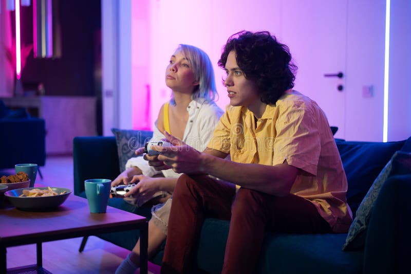 Happy boyfriend and girlfriend playing video games and holding