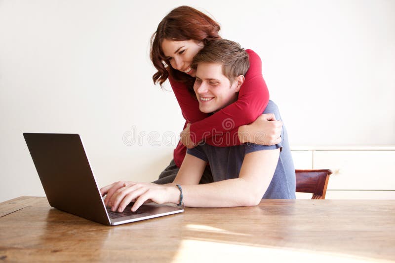 Happy boyfriend and girlfriend using laptop computer at home stock photos