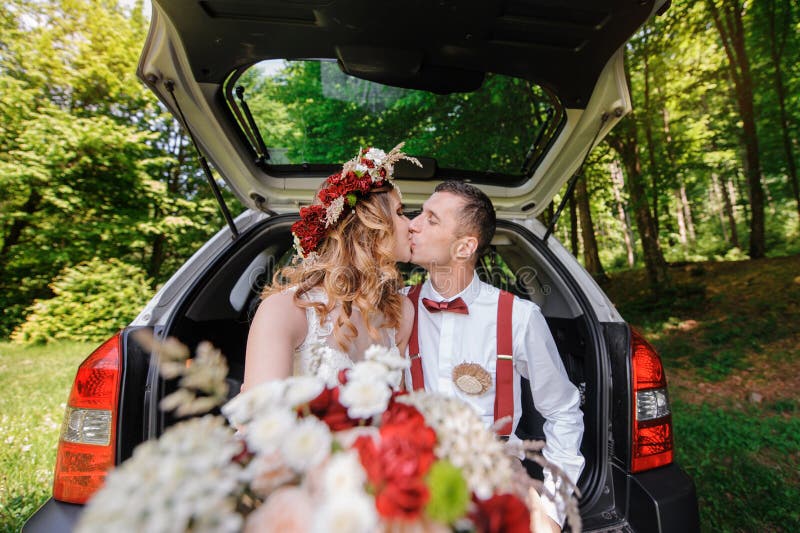 Happy bride and groom sitting in the trunk of a car stock photo Happy bride and groom sitting in the trunk of a car stock photo