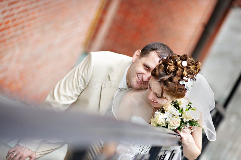 Happy bride and groom on stairs in park