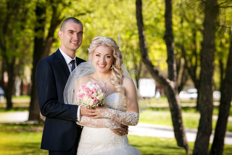 Happy Groom And The Charming Bride With A Bouquet From Roses In Studio ...