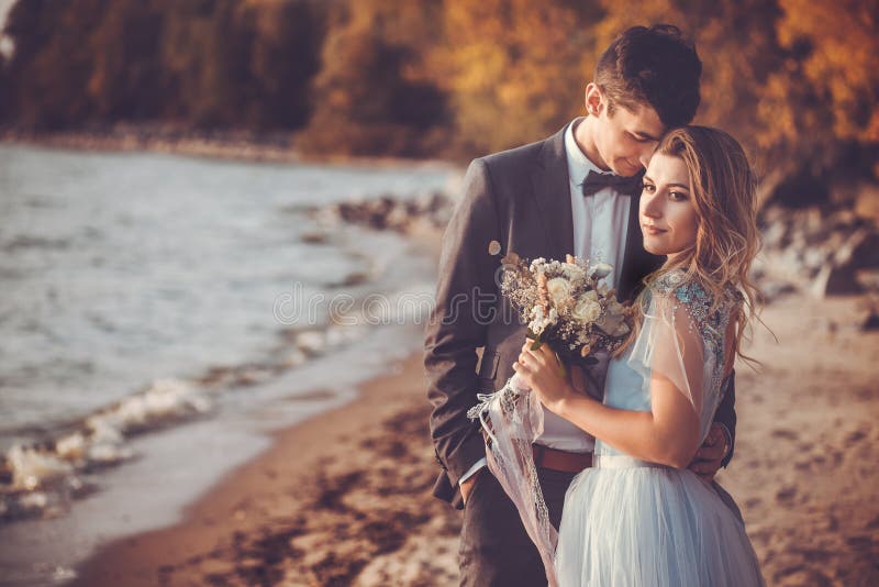 Newlyweds are walking on the autumn beach