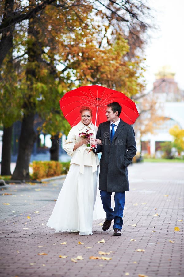 Happy bride and groom walking in park