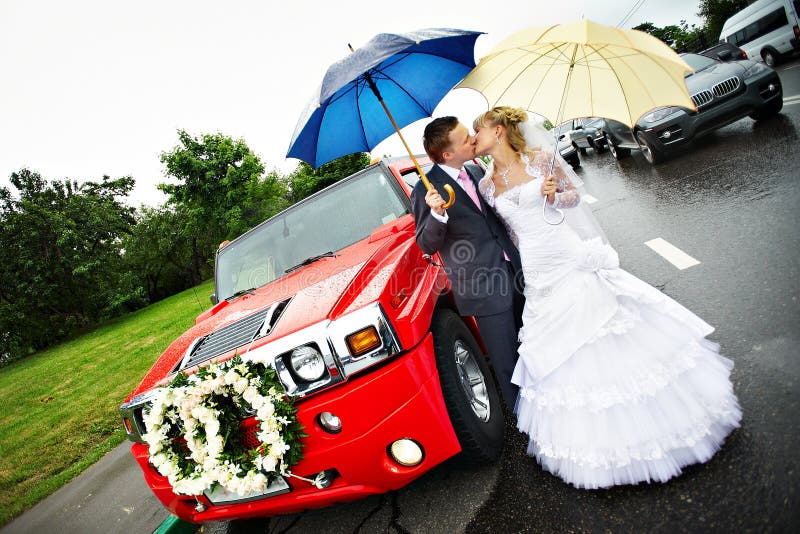 Happy bride and groom at wedding and red limo