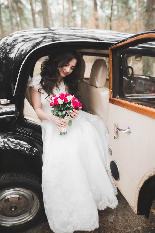 Happy bride in the retro car posing on her weeding day.