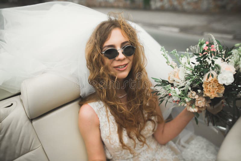 Happy bride in the retro car posing on her weeding day.